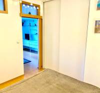 Interiér 2-pokojového bytu s posuvnými dveřmi a podlahou s dřevěným dekorem.