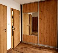 Chodba s podlahou s dřevěným dekorem a zrcadlem ve 3-pokojovém bytě.