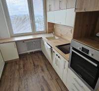 Kuchyně ve 3-pokojovém bytě s podlahou s dřevěným dekorem a moderními spotřebiči.