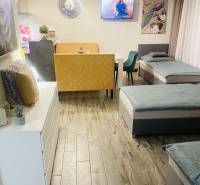 Obývací prostor v rodinném domě s pohovkou, křeslem, televizorem a podlahou s dřevěným dekorem.