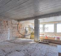 Staveniště v budově s cihlovými stěnami a velkými okny. Stavba je ve fázi výstavby.