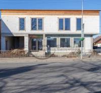 Budova ve Velkých Levárech s nedokončenou fasádou stojící u cesty.