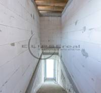 Pohled na schodiště v budově s betonovými stěnami a oknem na konci.