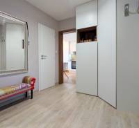 Předsíň 3pokojového bytu s velkým zrcadlem, lavičkou a podlahou s dřevěným dekorem.