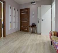 Předsíň v 3-pokojovém bytě s podlahou s dřevěným dekorem a barevnou lavicí.