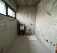 Nedokončená koupelna v rodinném domě s výhledem přes okno.