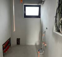 Pokoj v rodinném domě s rozvody a malým oknem, probíhá proces rekonstrukce.