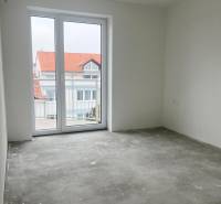 Prázdná místnost s šedou podlahou a velkým oknem ve 3-pokojovém bytě.