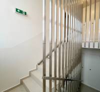 Schodiště se zábradlím a únikovou značkou ve 2-pokojovém bytě.