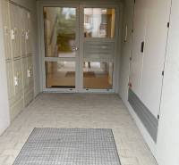 Vchod do bytového domu na Školské ulici v Chorvatském Grobu, s uzamykatelnými schránkami.