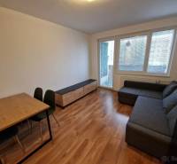 Obývací pokoj s rohovou sedačkou, jídelním stolem a podlahou s dřevěným dekorem v 2pokojovém bytě.