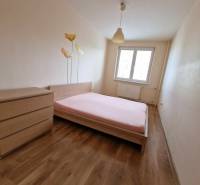 Ložnice v 2-pokojovém bytě s podlahou s dřevěným dekorem a květinovým motivem na stěně.