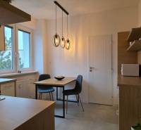 Kuchyně ve 3-pokojovém bytě s podlahou s dřevěným dekorem a závěsnými svítidly.