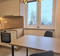 Kuchyně s kuchyňskou linkou, jídelním stolem a židlemi, ve 3-pokojovém bytě s podlahou s dřevěným dekorem.