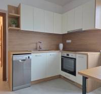 Kuchyně v 3-pokojovém bytě s bílými skříňkami a podlahou s dřevěným dekorem.