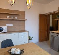 Kuchyně se stolem a židlí ve 3-pokojovém bytě, s dřevěným dekorem a mikrovlnkou.