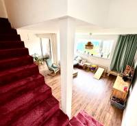 Interiér rodinného domu se schodištěm a obývacím pokojem s podlahou s dřevěným dekorem.