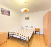 Ložnice v 2-pokojovém bytě s postelí, skříní a podlahou s dřevěným dekorem.