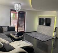 Obývací pokoj v rodinném domě s pohovkou a televizorem na stěně s kamenným obkladem.