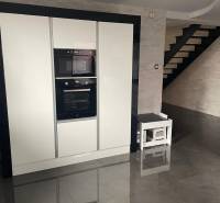 Kuchyně v rodinném domě s lesklou černou podlahou a bílými spotřebiči.