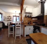 Kuchyně a obývací pokoj v rodinném domě s podlahou s dřevěným dekorem a bílým nábytkem.