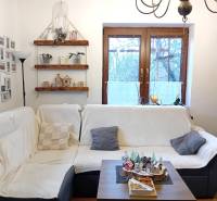 Obývací pokoj v rodinném domě s pohovkou, fotogalerií, policemi a dekoracemi.