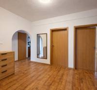 Chodba s podlahou s dřevěným dekorem a dřevěnými dveřmi ve 4pokojovém bytě.