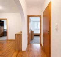 Chodba s podlahou s dřevěným dekorem, dveře vedou do pokojů ve 4pokojovém bytě.