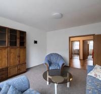 Obývací pokoj s pohovkou, skříní a stolkem ve 4pokojovém bytě.