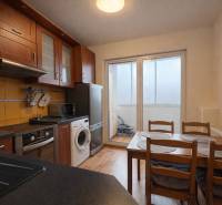 Kuchyně ve 4-pokojovém bytě s tmavým nábytkem a podlahou s dřevěným dekorem.