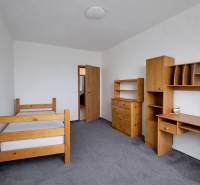 Pokoj ve 4pokojovém bytě se světlým nábytkem a šedým kobercem.