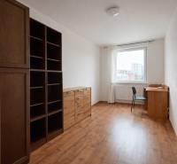 Pokoj ve 4pokojovém bytě s podlahou s dřevěným dekorem a nábytkem z tmavého dřeva.