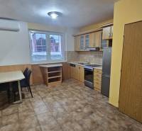 Kuchyně v 3-pokojovém bytě s kuchyňskou linkou, jídelním stolem a dlažbou.