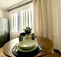 Jeden útulný kout 1-pokojového bytu s kulatým stolem a nádobím.