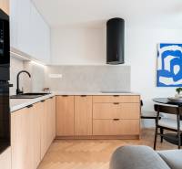 Kuchyně s podlahou s dřevěným dekorem, dřevěnými skříňkami a jídelním stolem ve 3-pokojovém bytě.