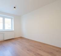 Světlý pokoj s podlahou s dřevěným dekorem v 3-pokojovém bytě se světlem nad oknem.