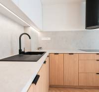 Kuchyňská linka v 3-pokojovém bytě s podlahou s dřevěným dekorem a černým dřezem.