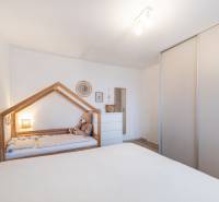 Dětský pokoj v dvoupokojovém bytě s dětskou postelí a skříní.