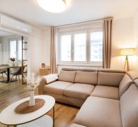 Světlý obývací prostor v 2-pokojovém bytě s podlahou s dřevěným dekorem a pohodlnou sedačkou.