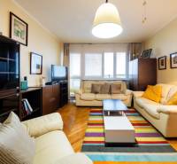 Obývací pokoj v 3-pokojovém bytě s koženými sedačkami a podlahou s dřevěným dekorem.