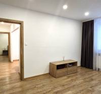 Pokoj v 3-pokojovém bytě s podlahou s dřevěným dekorem, světlem a nábytkem.