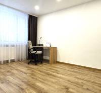 Pracovní kout s psacím stolem ve 3-pokojovém bytě s podlahou s dřevěným dekorem.