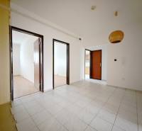 Interiér 4-pokojového bytu s bílými stěnami, dlažbou a podlahou s dřevěným dekorem.