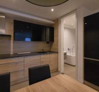 Kuchyně v 2pokojovém bytě s podlahou s dřevěným dekorem a instalovanou televizí.