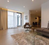 Obývací pokoj v 2-pokojovém bytě s pohodlnou sedačkou, křeslem a skleněným stolkem.