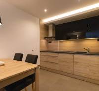 Kuchyně 2pokojového bytu s minimalistickým designem, dřevěným dekorem a jídelním stolem.