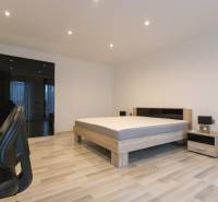 2pokojový byt s podlahou s dřevěným dekorem, postelí, skříní a kancelářskou židlí.