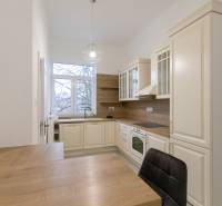 Kuchyně v 3-pokojovém bytě s podlahou s dřevěným dekorem a klasickými kuchyňskými skříňkami.