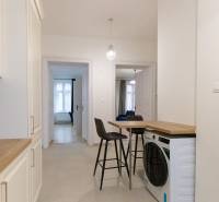 Chodba v 3-pokojovém bytě s pračkou, židlemi a kuchyňskou linkou.