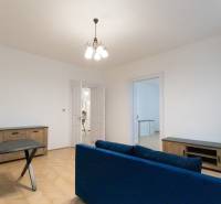 Obývací pokoj v 3pokojovém bytě s podlahou s dřevěným dekorem a modrou pohovkou.